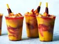 Färgglada mangodrycker med chili och fruktbitar. En perfekt guide för como hacer mangoneadas!