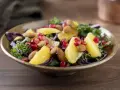En färgstark sallad med apelsinklyftor, granatäppelkärnor, mandlar och olika typer av lechuga som grönkål och rödkål.