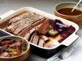 Skivad, saftig **pecho de res** med rostade rödbetor och en skål med sås. En härlig måltid.