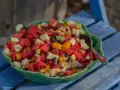En stor skål med en färgglad ensalada de frutas, fylld med vattenmelon, äpple, apelsin, banan och granatäpple.