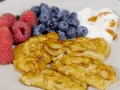 En tallrik med gyllene pannkakor, färska hallon, blåbär och en klick yoghurt med kanel. Perfekt för cenas para diabeticos.