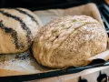 Två olika tipos de pan dulce, en med vallmofrön och en flätad med sesamfrön, redo att bakas.