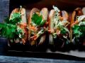 Fyra läckra korv med bröd, toppade med krispig kål, morötter och persilja. Enkel guide: como hacer un hot dog.