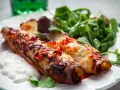 Två gyllene enchiladas, en typisk maträtt från Guatemala, serveras med en fräsch sallad och en klick gräddfil.