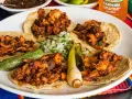 Fajitas de pollo con vegetales på en tallrik, med en läsk och salsa i bakgrunden.