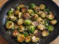 Stekta coles de bruselas med vitlök och parmesan i en gjutjärnspanna.