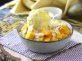 En skål med tärnad mango och en kula vaniljglass, toppad med mandelflagor. En härlig mango en miel-dessert.