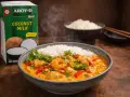 En skål med ångande curry med räkor, kyckling och grönsaker, serverad med ris. Bredvid står en kartong med Aroy-D kokosmjölk, perfekt för en krämig leche de coco-baserad sås.