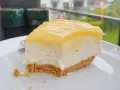 En bit krämig cheesecake med gul topping, perfekt för den som vill lära sig como hacer un cheesecake.