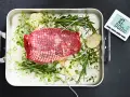 Råstek med örter och vitlök, redo för ugnen. En köttermometer visar 10°C.