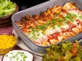 Enchiladas i ugnsform, toppade med smält ost och persilja. Tillbehör: majs, sallad och gräddfil. Perfekt för en middag med tortillas para enchiladas.