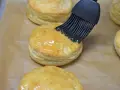 Pensel applicerar glansig glasyr på gyllene, flagnande pastelitos de carne.
