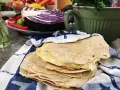 Färska tortillas de harina, redo att fyllas med goda ingredienser. I bakgrunden syns rödkål, chili och koriander.