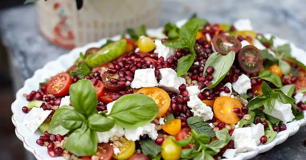 En färgstark sallad med granatäpple, tomater, fetaost och basilika. Perfekt för att visa para qué sirve la ensalada – en hälsosam och god måltid!