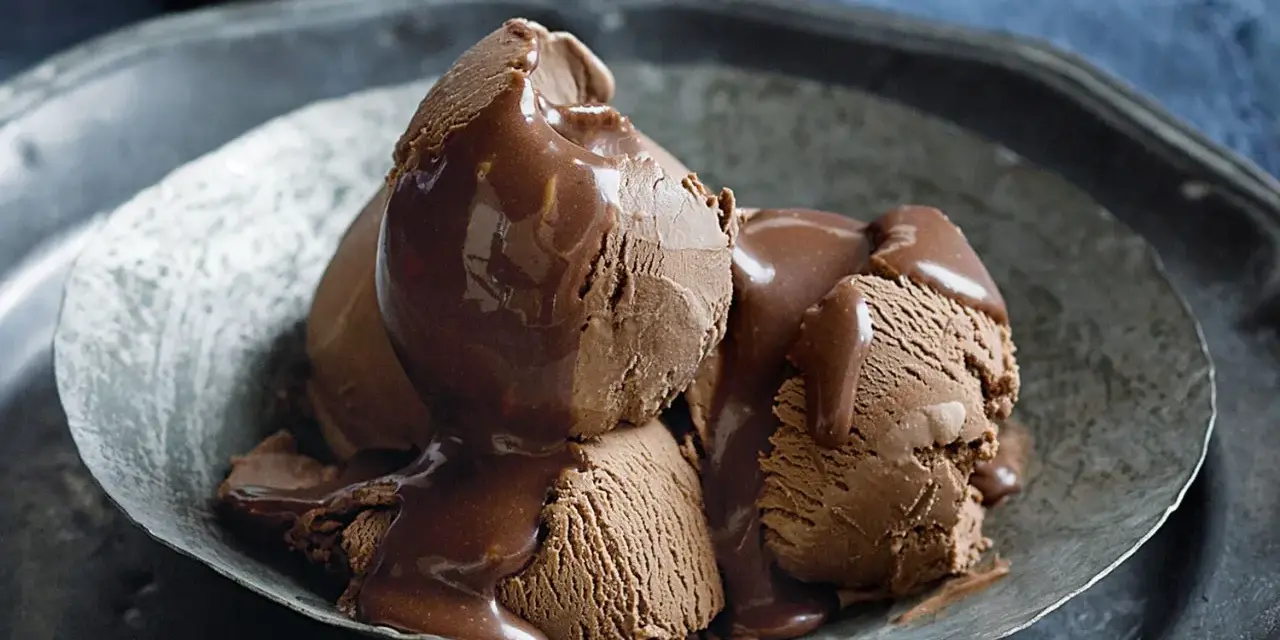Tre kulor chokladglass, rikligt täckta med varm chokladsås, serveras i en rustik skål. En dröm för alla som älskar helado de chocolate.
