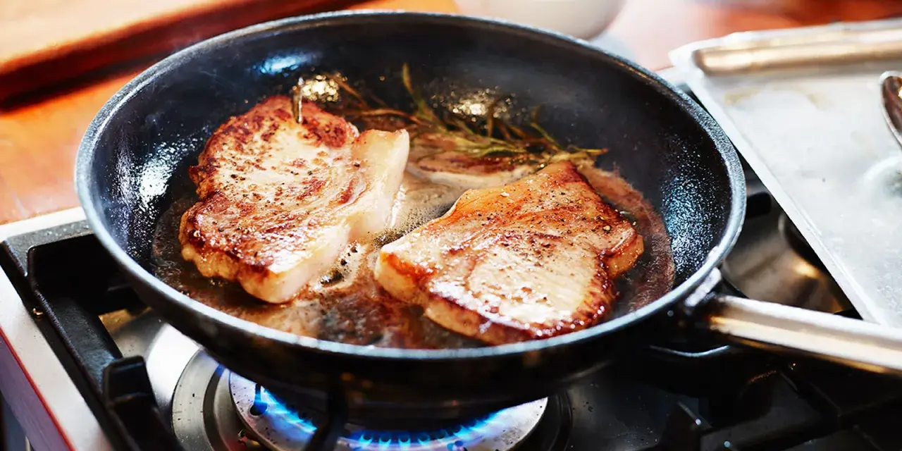 Två saftiga biffar steks i en panna med rosmarin. En perfekt guide för como hacer bistec de carne.