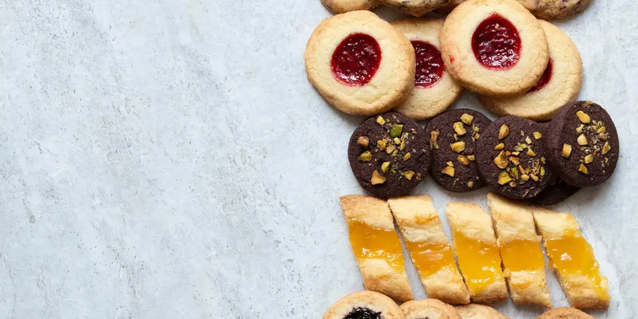 En variation av olika tipos de galletas: syltkakor, chokladkakor med nötter och småkakor med marmelad.