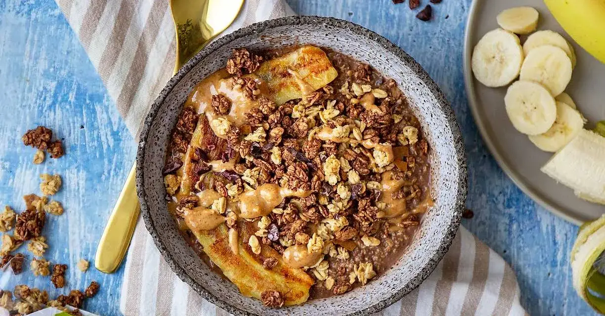 En skål med gröt, banan, granola och jordnötssmör. Perfekt för hälsosamma frukostar.