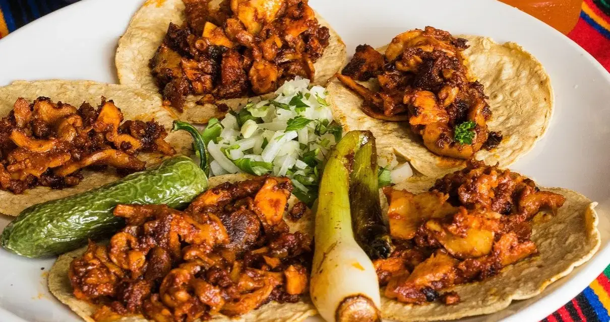 Fajitas de pollo con vegetales på en tallrik, med en läsk och salsa i bakgrunden.