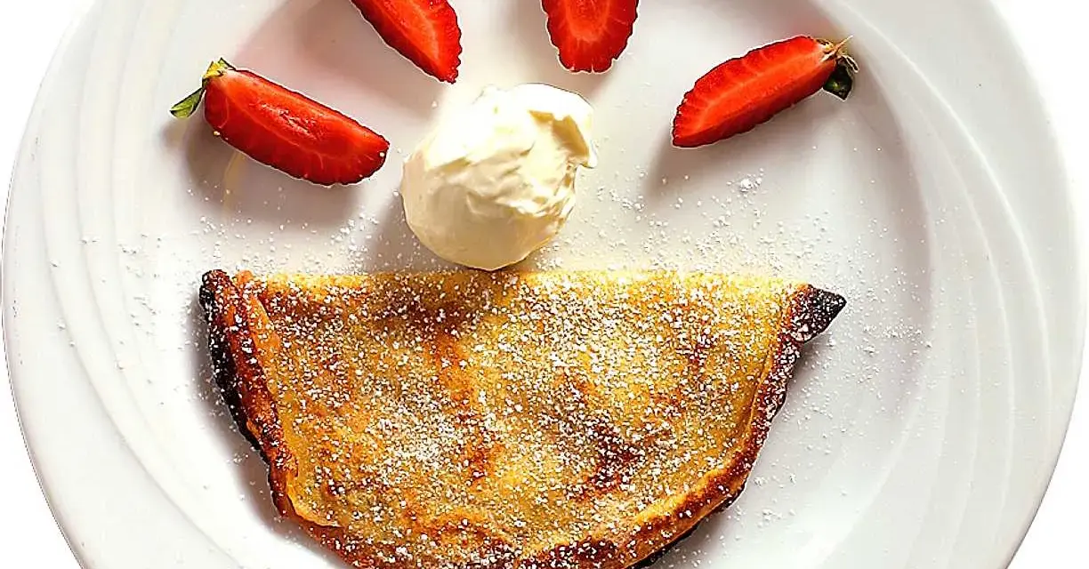 En glad pannkaka med jordgubbar och grädde. Crepas de fresa som ser ut som ett leende.
