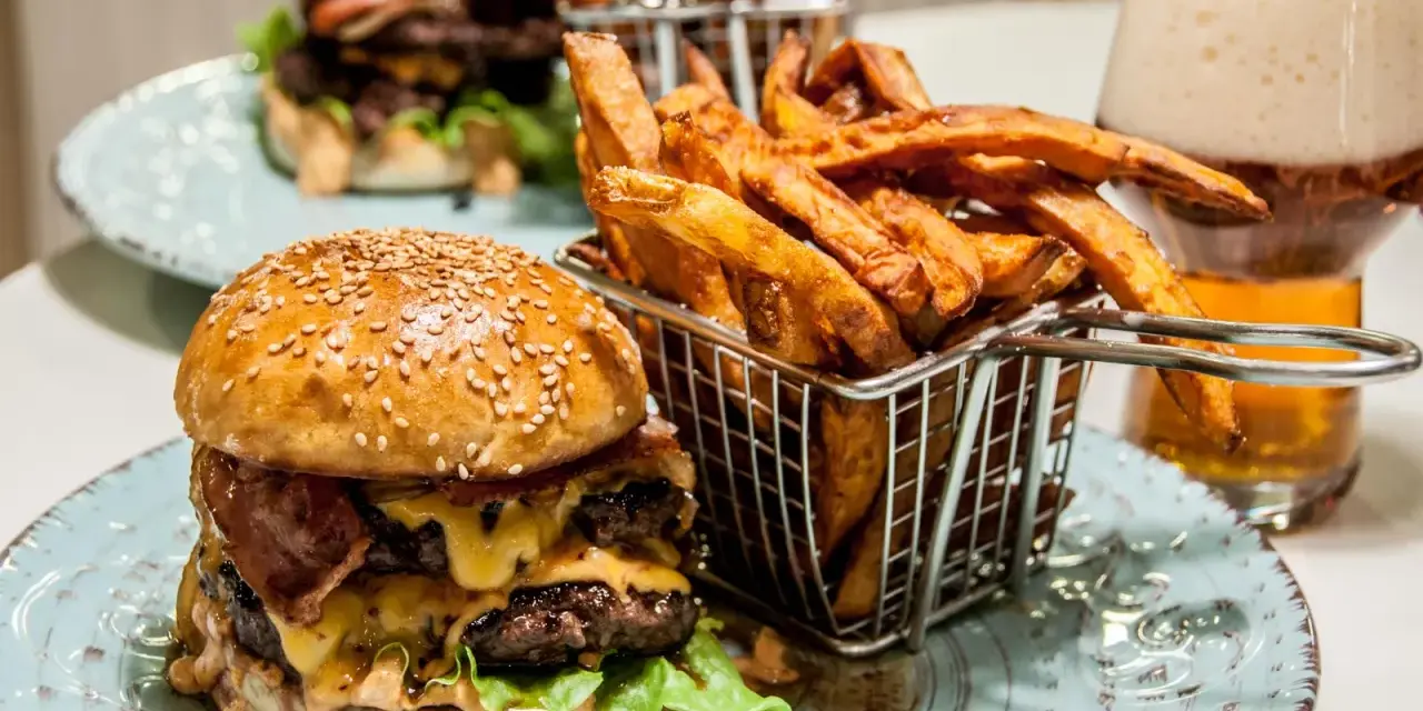 En saftig hamburguesa con papas frites i en korg, redo att avnjutas. En perfekt måltid för en hungrig själ.