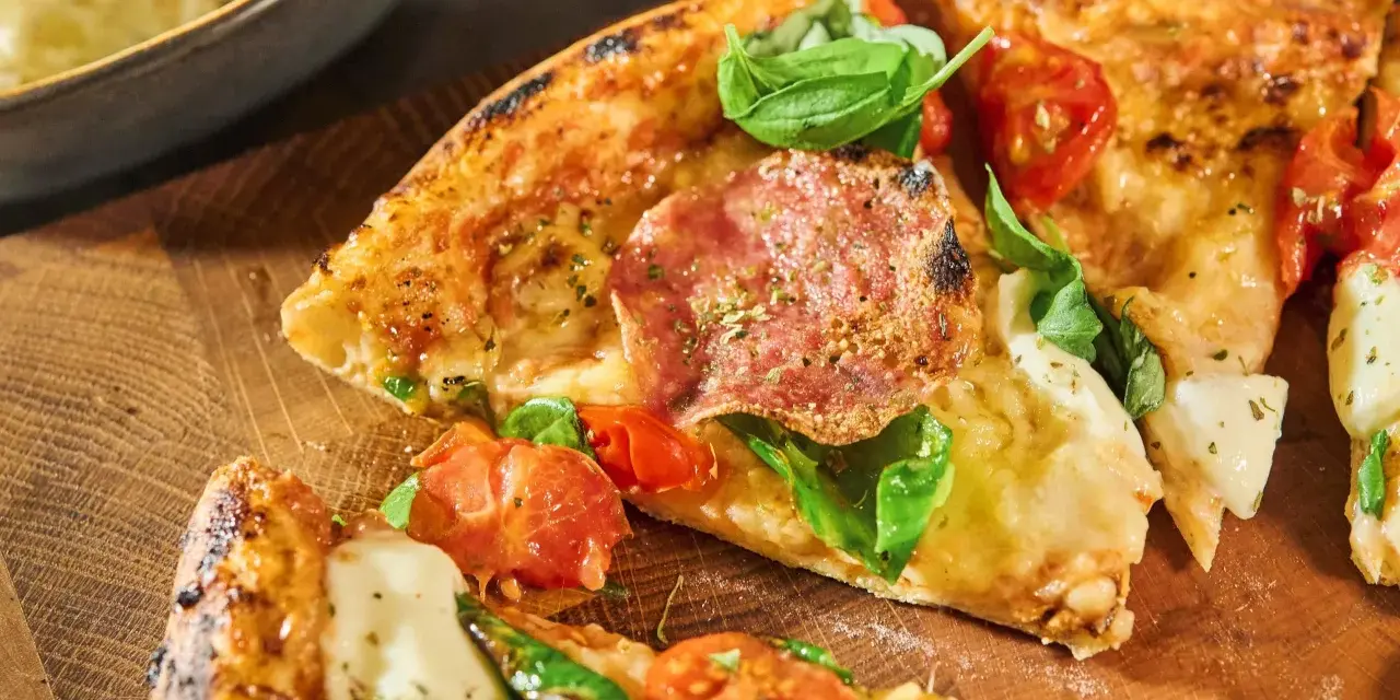 Njut av en utsökt pizza med färska **ingredientes para pizza** som salami, tomater och basilika, serverad på en träskärbräda.