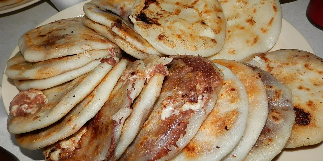 En tallrik med staplade pupusas salvadoreñas, gyllene och fyllda med läckra ingredienser.