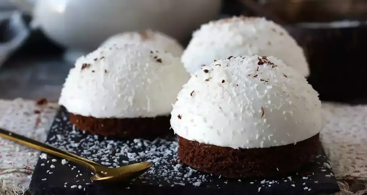 Tre små chokladbakelser med fluffig kokoskräm och strössel. En gyllene sked ligger redo för att njuta av dessa flan de coco.