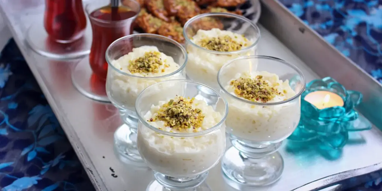 Fyra glas med krämig arroz en leche salvadoreño, toppad med pistagenötter. Två glas med te och en ljuslykta fulländar serveringen.