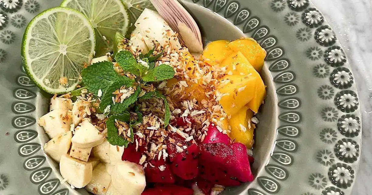 Fruktskål med mango, drakfrukt, banan, lime och mynta, toppad med rostad kokos. En härlig frukost som påminner om dulce de nance.