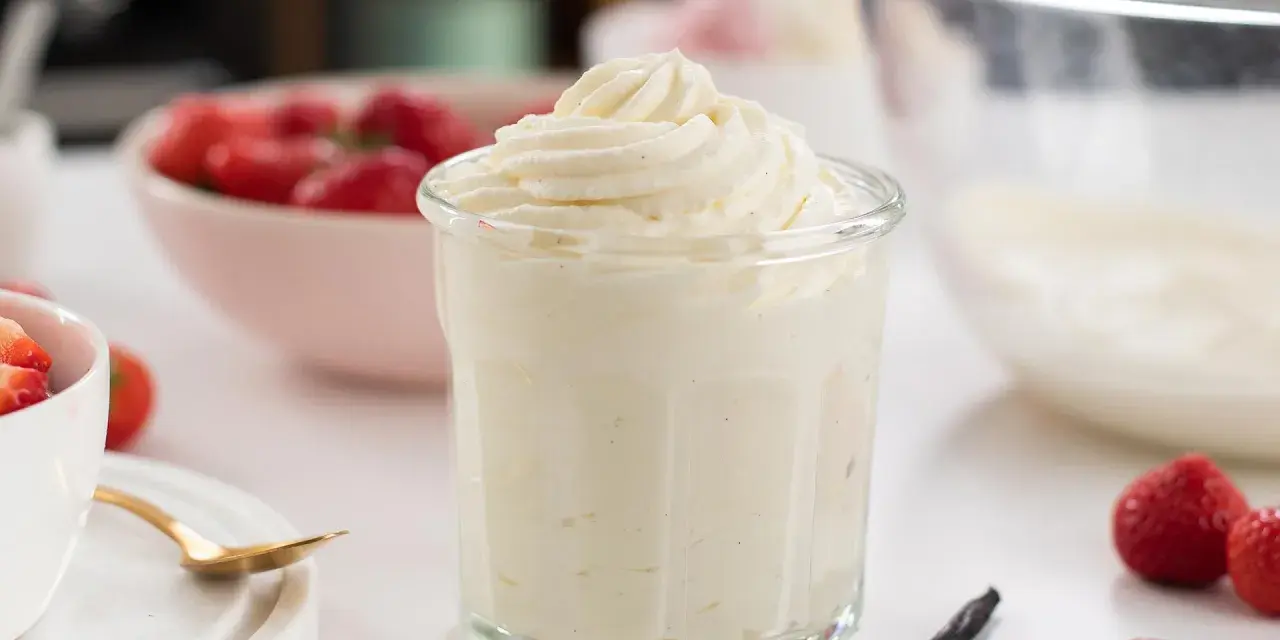En krämig crema chantilly i ett glas, omgiven av färska jordgubbar och vaniljstänger. Perfekt för sommardesserter.