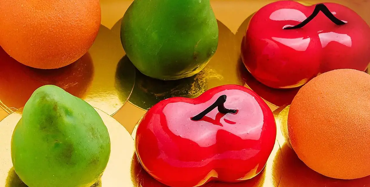 Sju glaserade bakverk i form av frukter: päron, körsbär och apelsiner. Dessa pasteles de frutas ser utsökta ut!