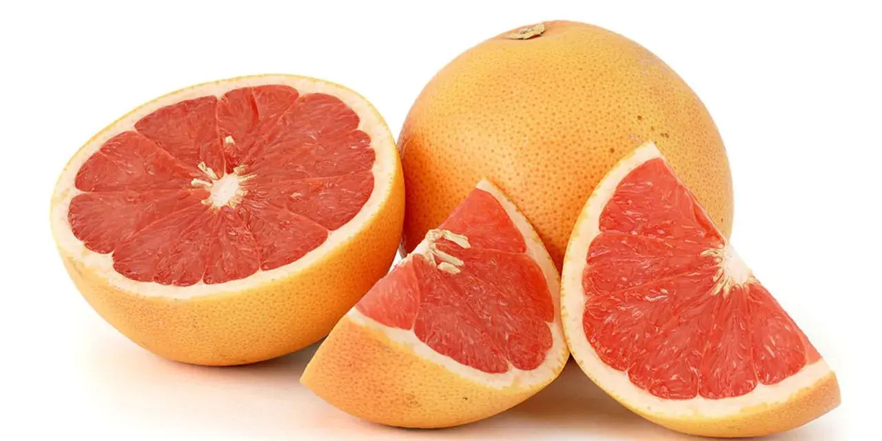 En hel och skivad rosa grapefrukt. Denna saftiga pomelo que es är en uppfriskande citrusfrukt.