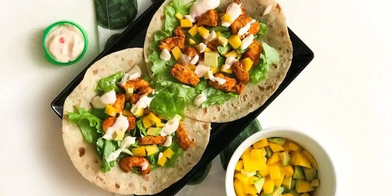 Två kycklingwraps med mango, avokado och sallad. En liten skål med mangosalsa. Hur många kalorier har en tortilla?