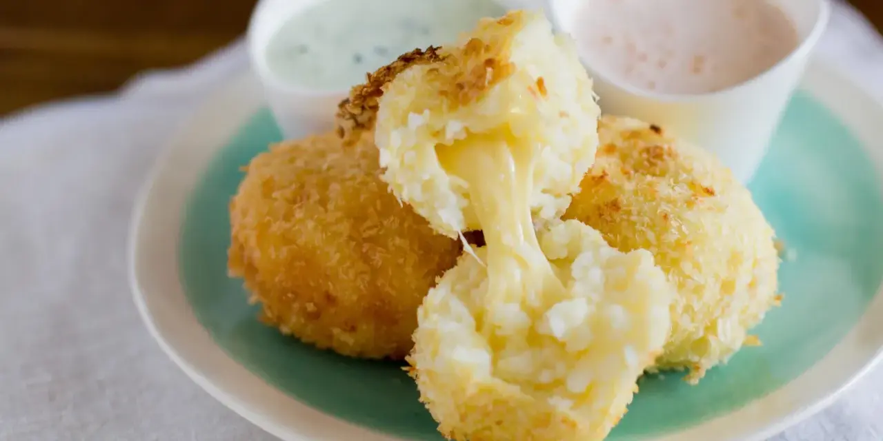Krispiga papas rellenas de queso med smält ost som rinner ut. Serveras med två dippsåser.