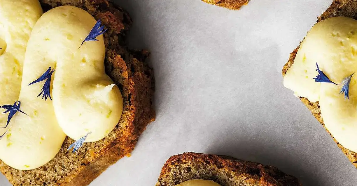 Skivor av saftig sockerkaka med fluffig citronkräm och blå blomblad. Perfekt för en fika, tack vare bakpulver som ger den luftiga konsistensen.