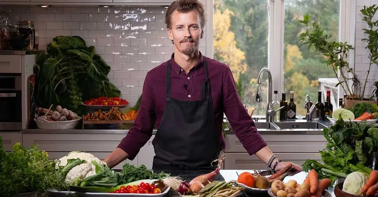 En kock i köket med ett överflöd av färska grönsaker, redo att visa olika tipos de cortes de vegetales.