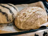 Två olika tipos de pan dulce, en med vallmofrön och en flätad med sesamfrön, redo att bakas.