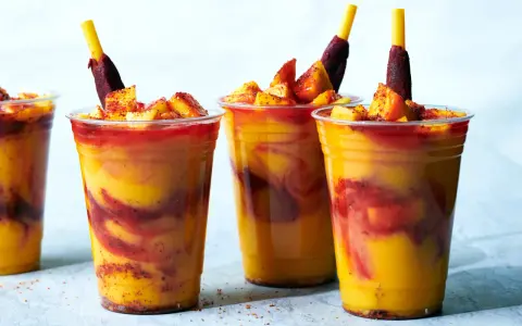Färgglada mangodrycker med chili och fruktbitar. En perfekt guide för como hacer mangoneadas!