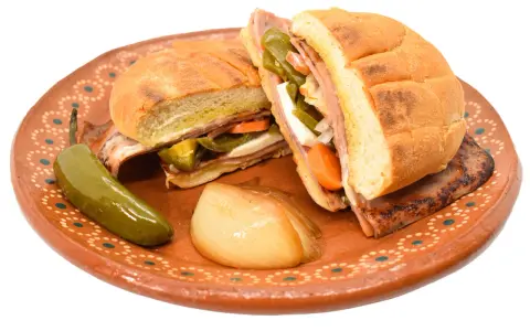 En saftig torta de jamón med jalapeños, morötter och ost på en vacker lertallrik.