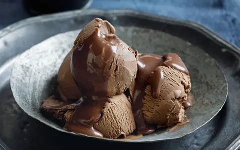 Tre kulor chokladglass, rikligt täckta med varm chokladsås, serveras i en rustik skål. En dröm för alla som älskar helado de chocolate.