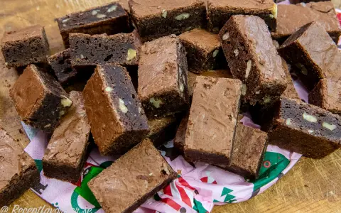 En hög med saftiga, hembakade pasteles de chocolate, vissa med nötter, ligger på ett mönstrat papper.