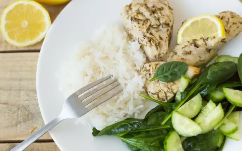 En tallrik med kycklingfilé, ris, spenat och gurka. Perfekt för cenas saludables para bajar de peso.
