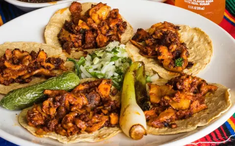 Fajitas de pollo con vegetales på en tallrik, med en läsk och salsa i bakgrunden.