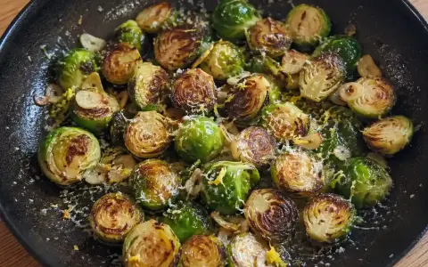 Stekta coles de bruselas med vitlök och parmesan i en gjutjärnspanna.