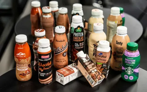 En samling flaskor och kartonger med olika sorters batido de proteinas, mestadels chokladsmak.