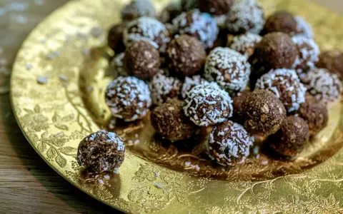 Chokladbollar med **harina de avena** (havregryn) på ett gyllene fat. En är uppäten.