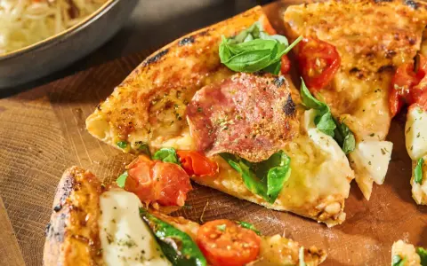 Njut av en utsökt pizza med färska **ingredientes para pizza** som salami, tomater och basilika, serverad på en träskärbräda.