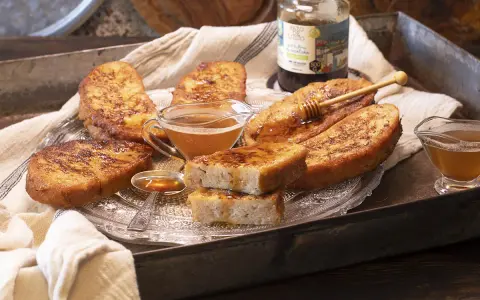 Gylla, gyllene torrejas en miel, serverade på ett fat med honung och en honungsstav.