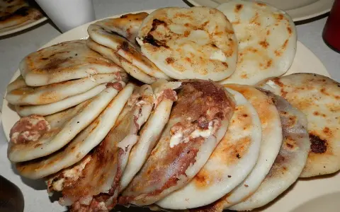 En tallrik med staplade pupusas salvadoreñas, gyllene och fyllda med läckra ingredienser.